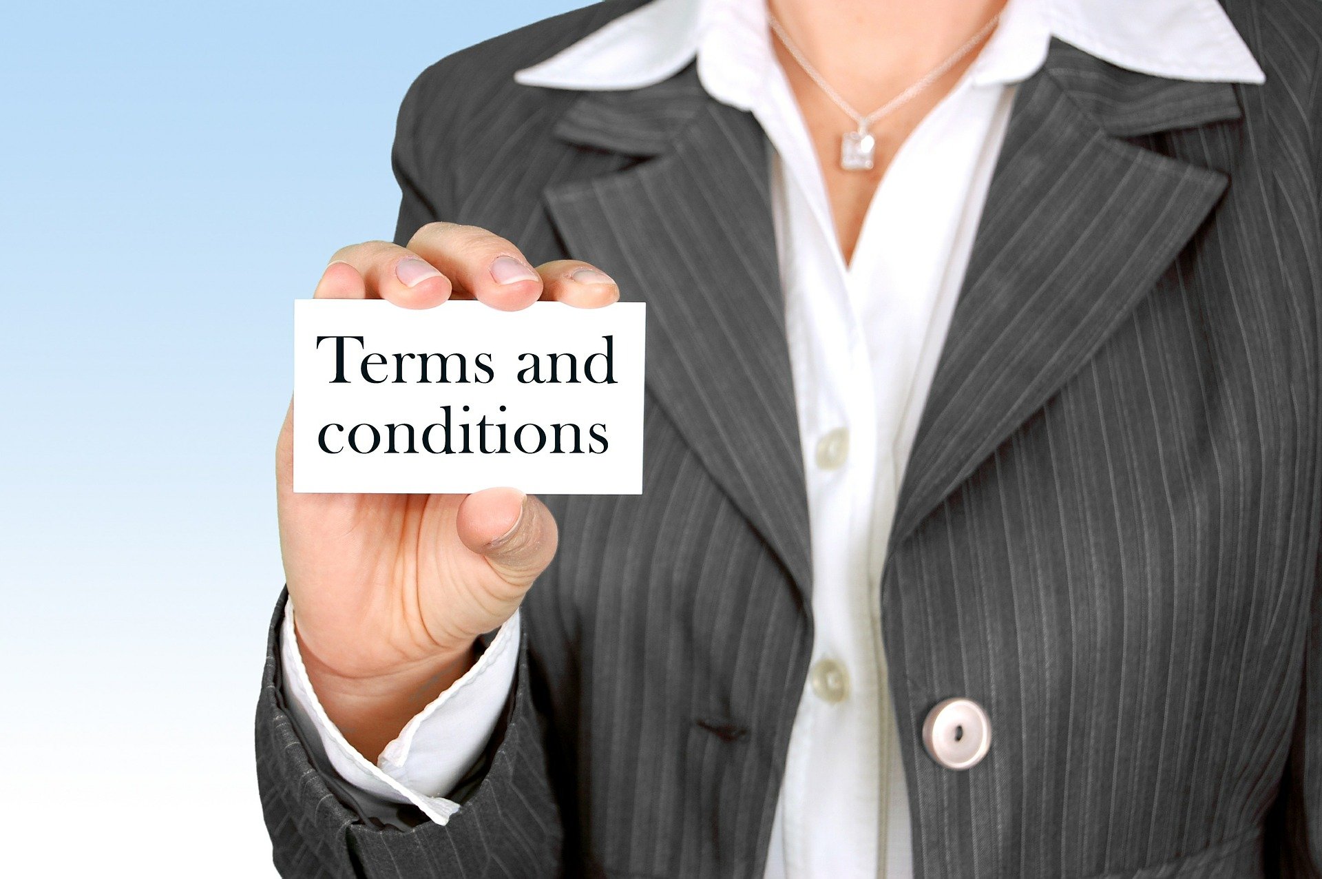 frau im blazer hält karte mit aufschrift "terms and conditions" in die kamera