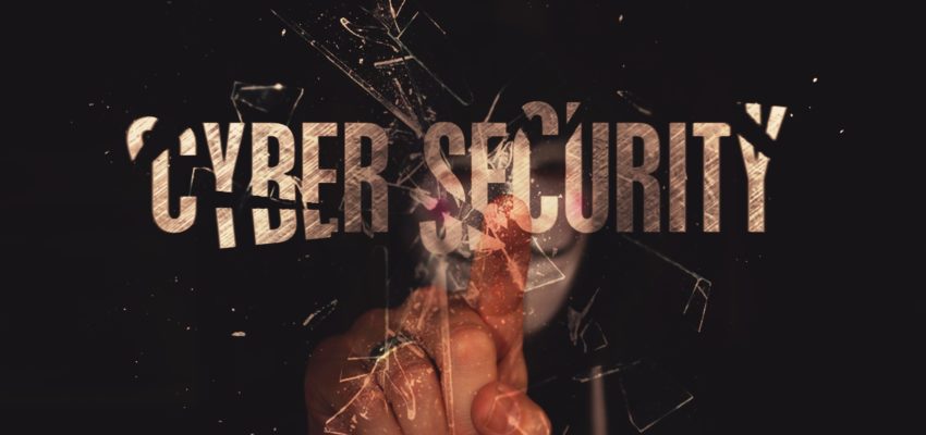 maskierter hacker zeigt auf den schriftzug cyber security